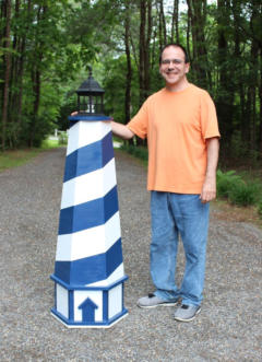 Me standing next to the blue and white striped lawn lighthouse after I built it